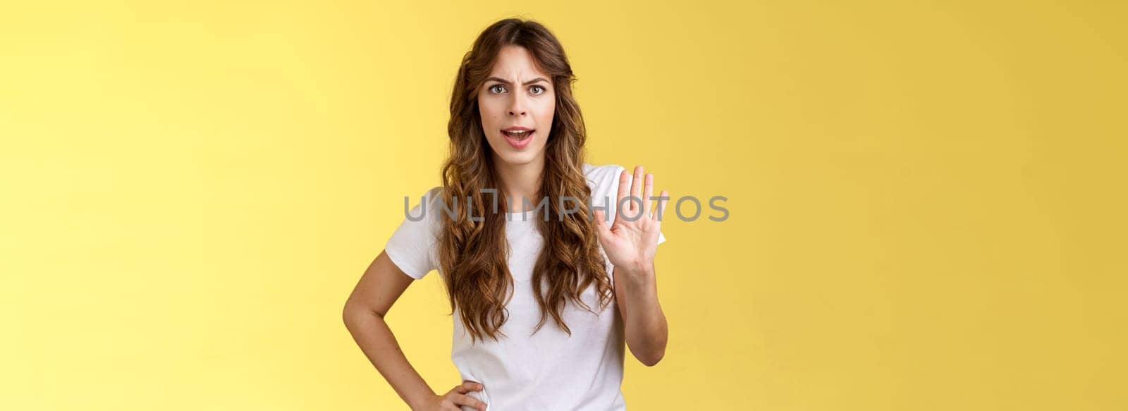 Hold it stop. Girl feeling intense serious grimacing demand end unpleasant conversation raise palm rejection refusal prohibit enough wasting my time frowning disappointed yellow background.