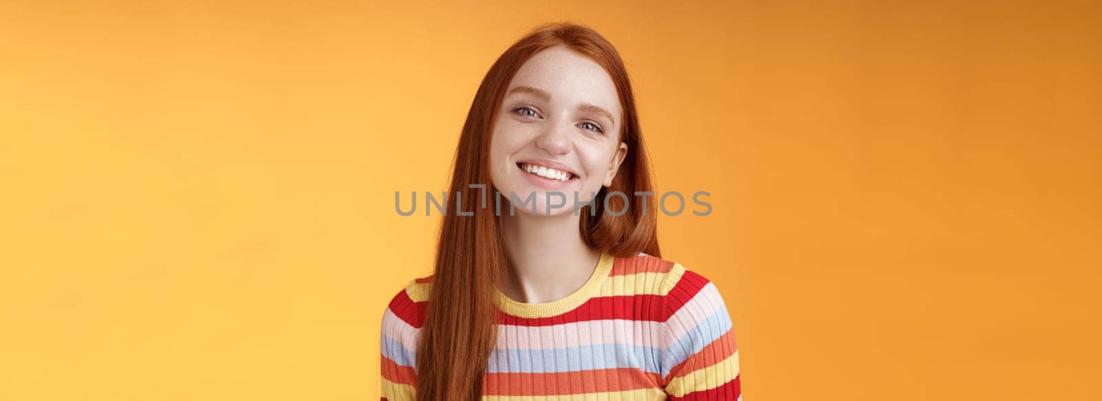 Friendly feminine pretty redhead caucasian female sibling smiling broadly have perfect happy mood talking casually enjoy fine summer sunny day standing orange background delighted relaxed.