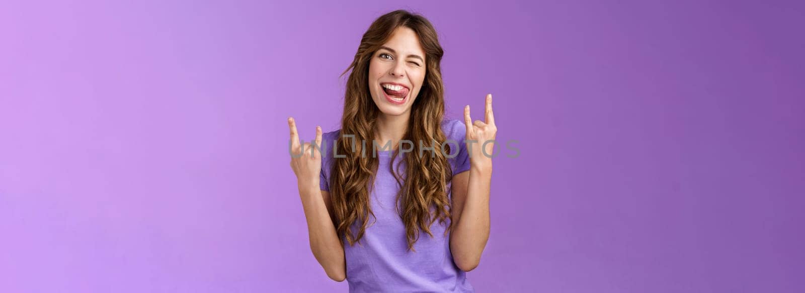 Daring sassy funny attractive woman having fun enjoy awesome party arrange music concert gathering show rock-n-roll heavy metal sign joyful stick tongue wink cheeky purple background. Lifestyle.