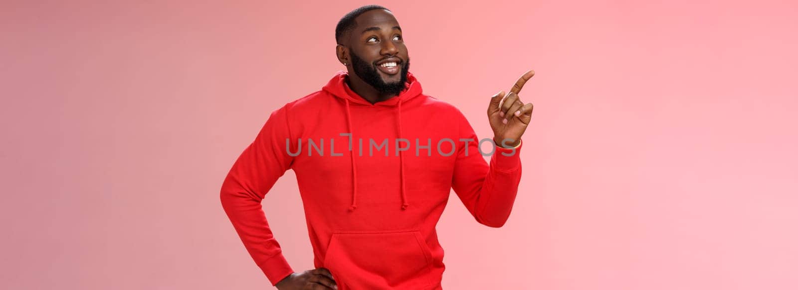 Happy charismatic delighted african-american bearded guy smiling white teeth look pointing intrigued upper left corner curious what interesting product standing impressed pink background by Benzoix