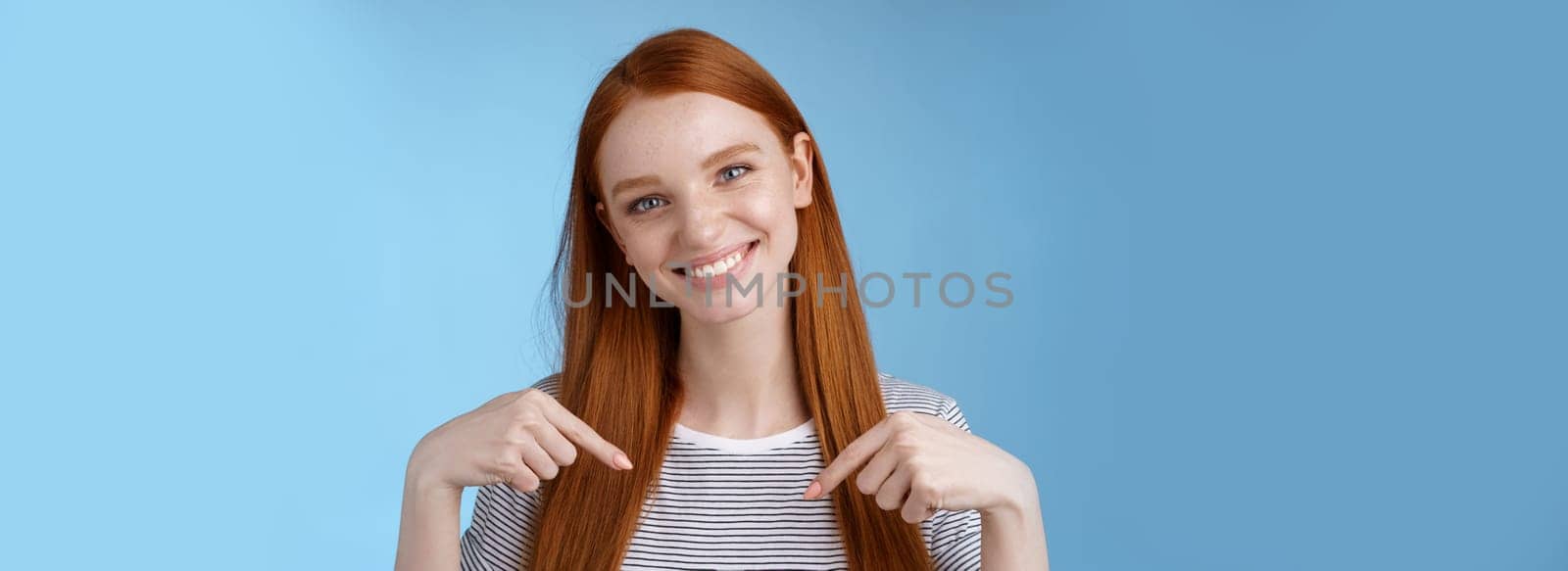 Visit place you love it. Friendly-looking kind gentle attractive redhead woman showing advertisement copy space pointing index fingers down tilting head smiling helpful recommend promo.
