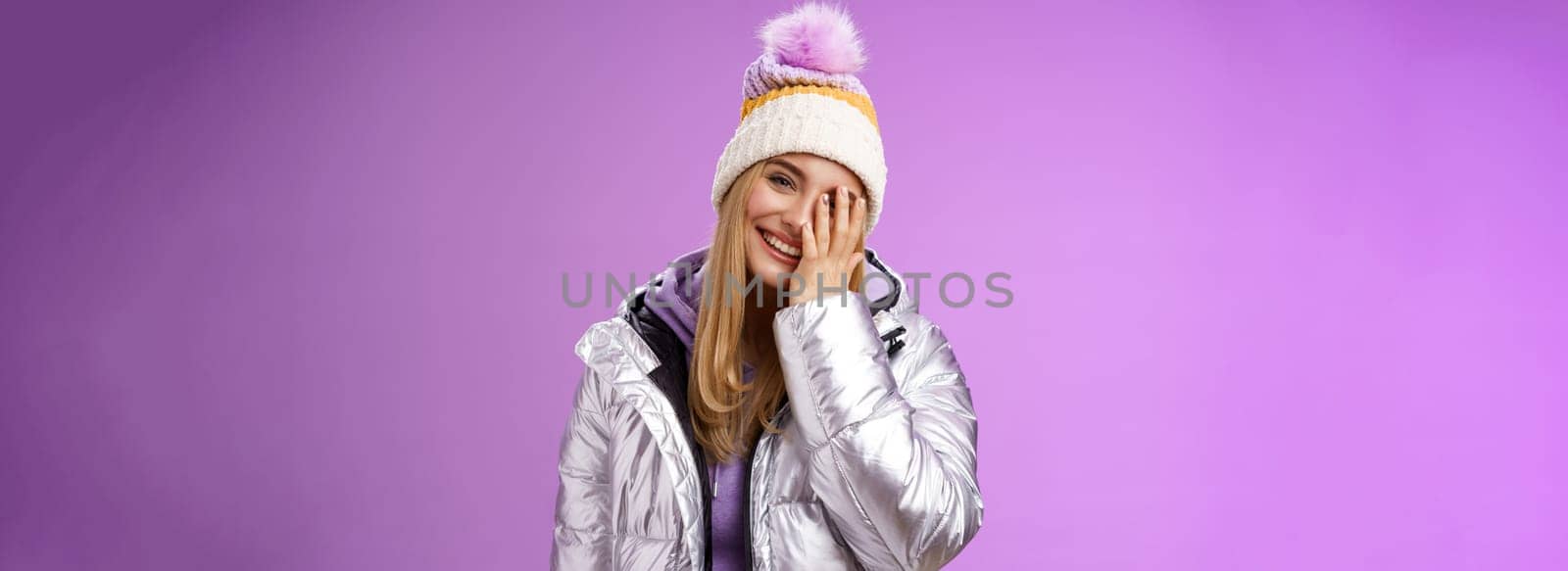 Carefree happy upbeat charming blond woman cover half face tilting head laughing joyfully wearing outdoor stylish silver jacket winter hat having fun awesome five star ski resort, purple background by Benzoix