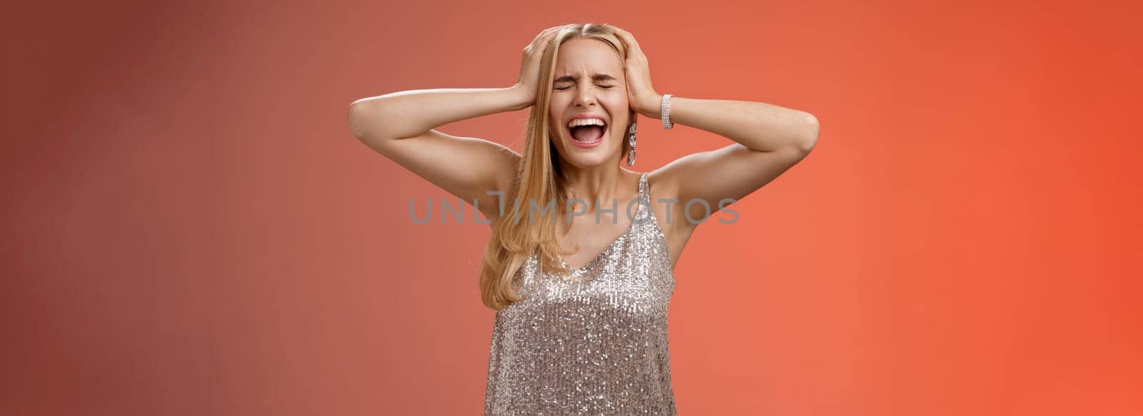 Lifestyle. Upset distressed pressured fed up panicking young blond woman in dress scream cry heart out being heartbroken close eyes hold hands head mentaly unstable standing sad depressed red background.