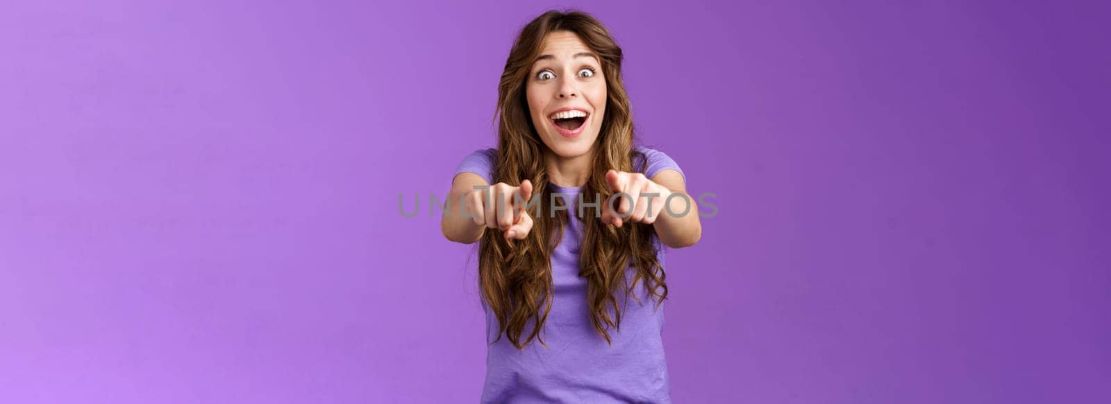 Omg its you. Surprised girl fan cheering joyfully gazing camera popping eyes pointing fingers forward astonished express admiration see superstar wanna receive autograph stand purple background by Benzoix