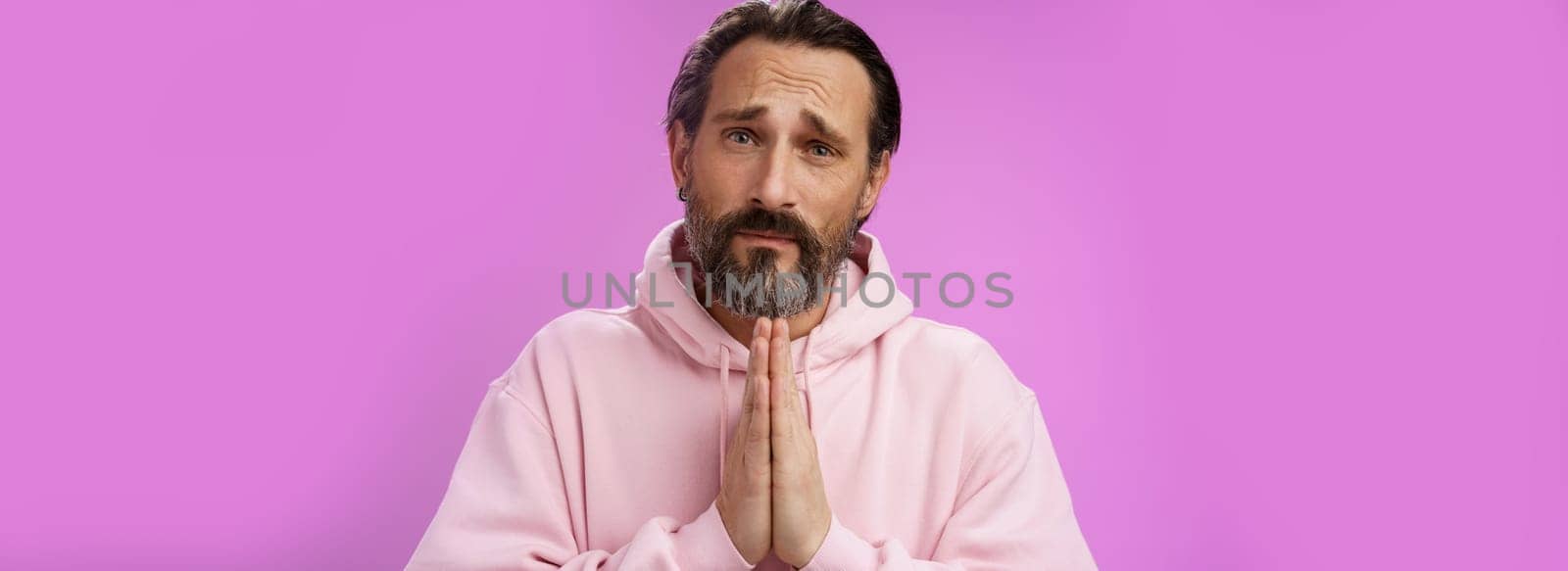 Upset handsome bearded mature man need help asking forgiveness supplicating press palms together praying frowning sorrow begging favour lend money, standing purple background miserable by Benzoix