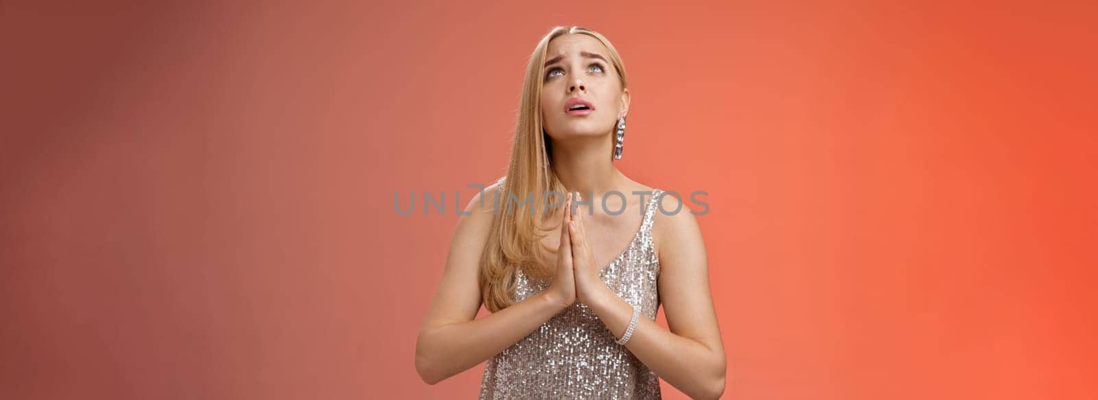 Hopeful worried concerned faithful blond woman in silver dress praying talking god wishing family okay press palms together supplicating nervously begging, standing red background stylish dress by Benzoix