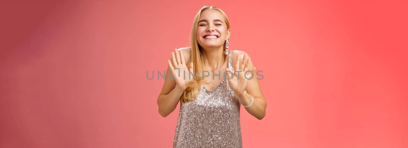 Lifestyle. Excited happy charming birthday blond girl celebrating having fun partying smiling broadly carefree closed eyes rejoice grin dancing raise palms head up standing joyful stylish silver dress.