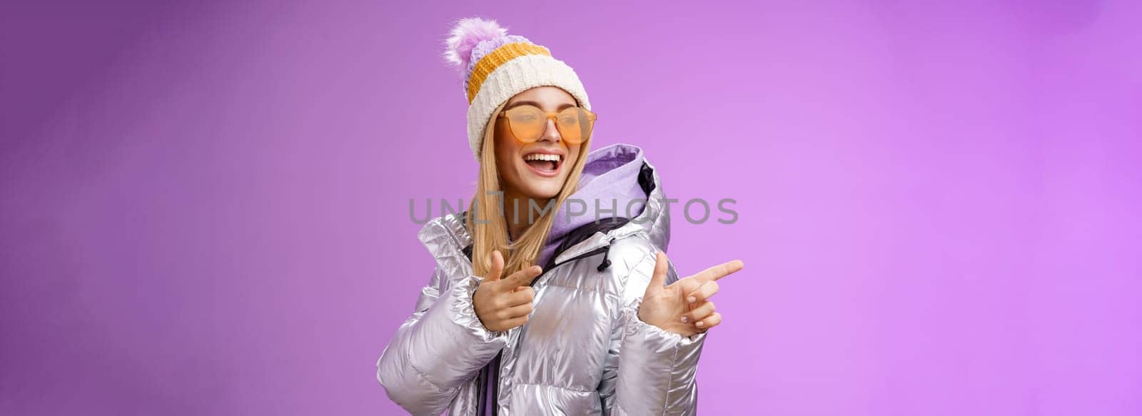 Hey how you doin. Cheeky stylish bond girl having fun greeting friend pointing finger pistols left smiling sassy say hello what up wearing cool silver jacket hat sunglasses, purple background by Benzoix