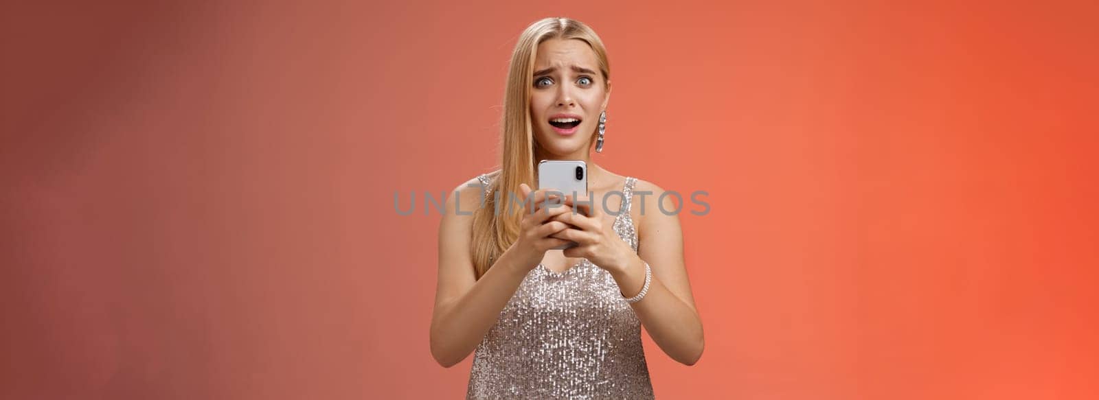 Panicking shocked woman concerned photos leaked internet look afraid anxious widen eyes cringing troubled hold smartphone shook speechless gasping terrified friends find out secret, red background.