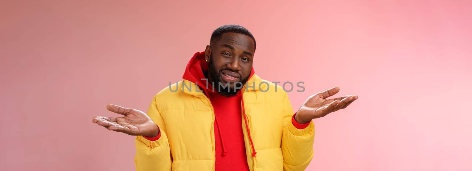 Close-up clueless unaware handsome stylish african-american bearded man in yellow jacket shrugging hands spread sideways dismay cannot understant anything standing perplexed, pink background.