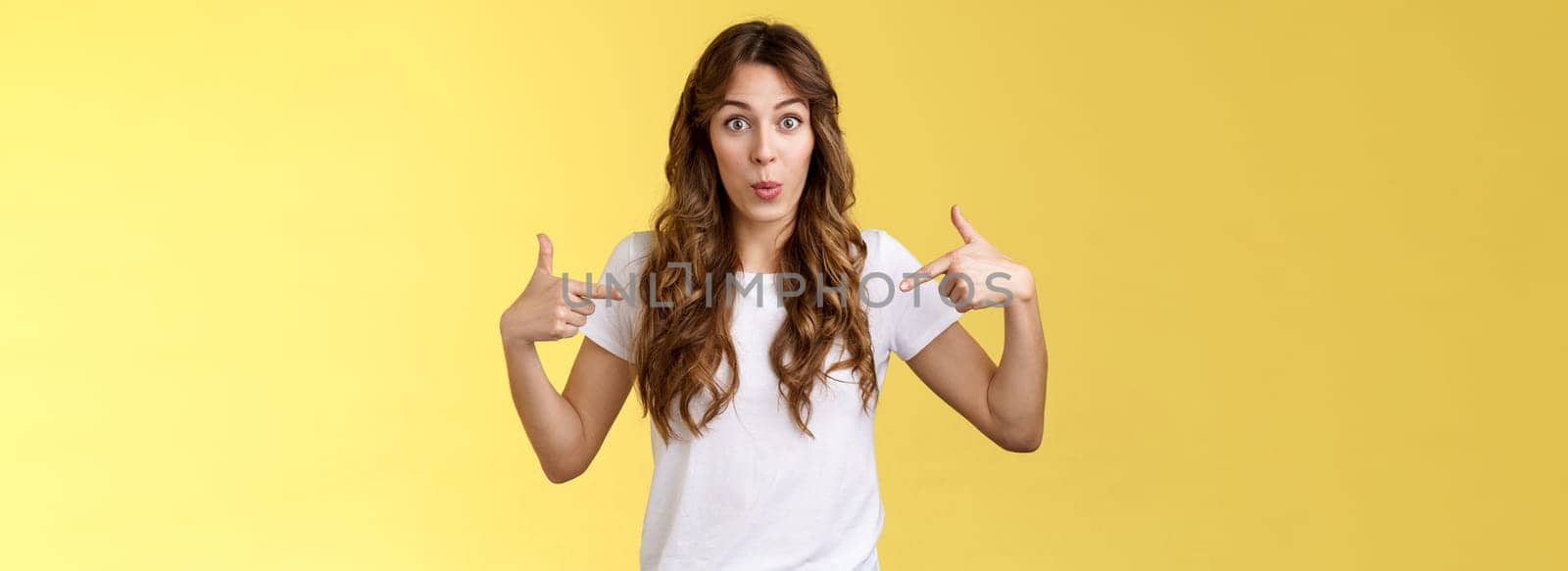 Wow just look. Impressed surprised cute wondered european girl pointing fingers center copy space white t-shirt folding lips amused astonished awesome promo great chance gaze you camera by Benzoix