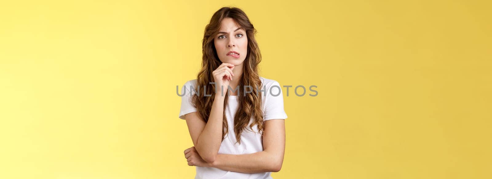 Troublesome situation give sec think. Intrigued thoughtful focused smart girlfriend thinking touch chin bite lip look camera focused pondering choice making decision solve problem yellow background by Benzoix