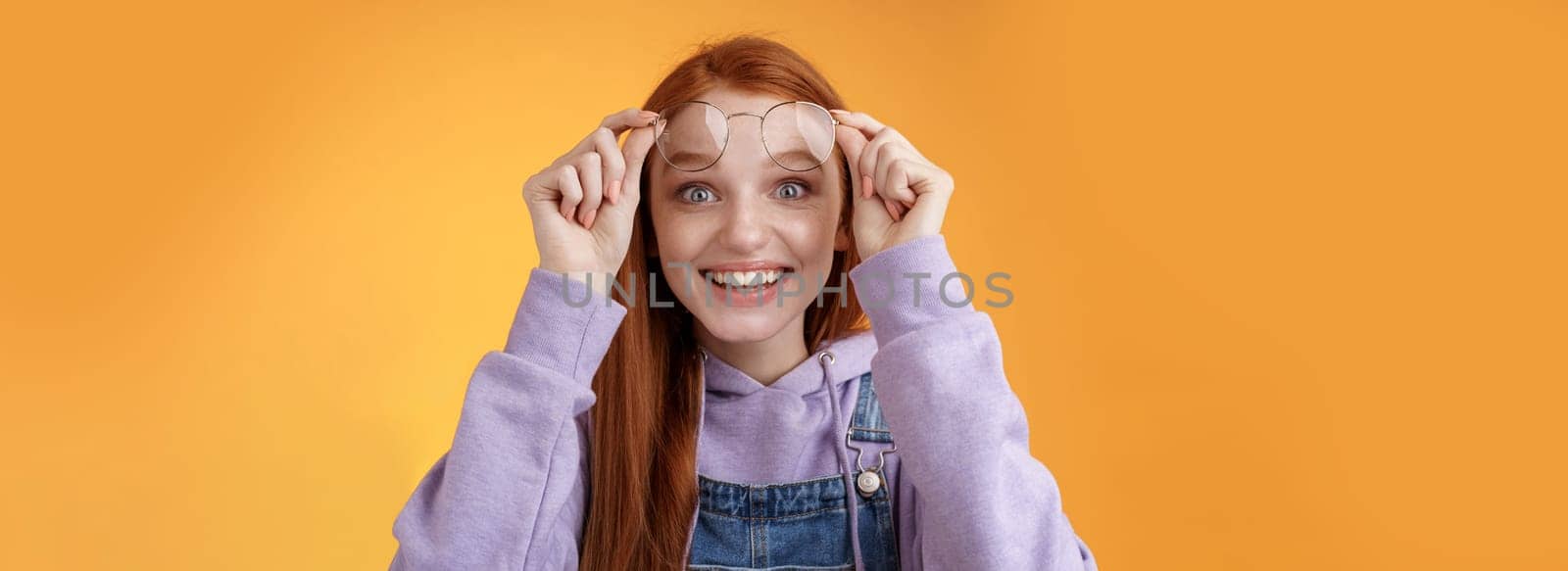 Impressed excited happy pleased young silly lovely redhead girl receive pleasing surprise take off glasses wide eyes touched smiling delighted gasping amazed feel upbeat thrilled. Copy space