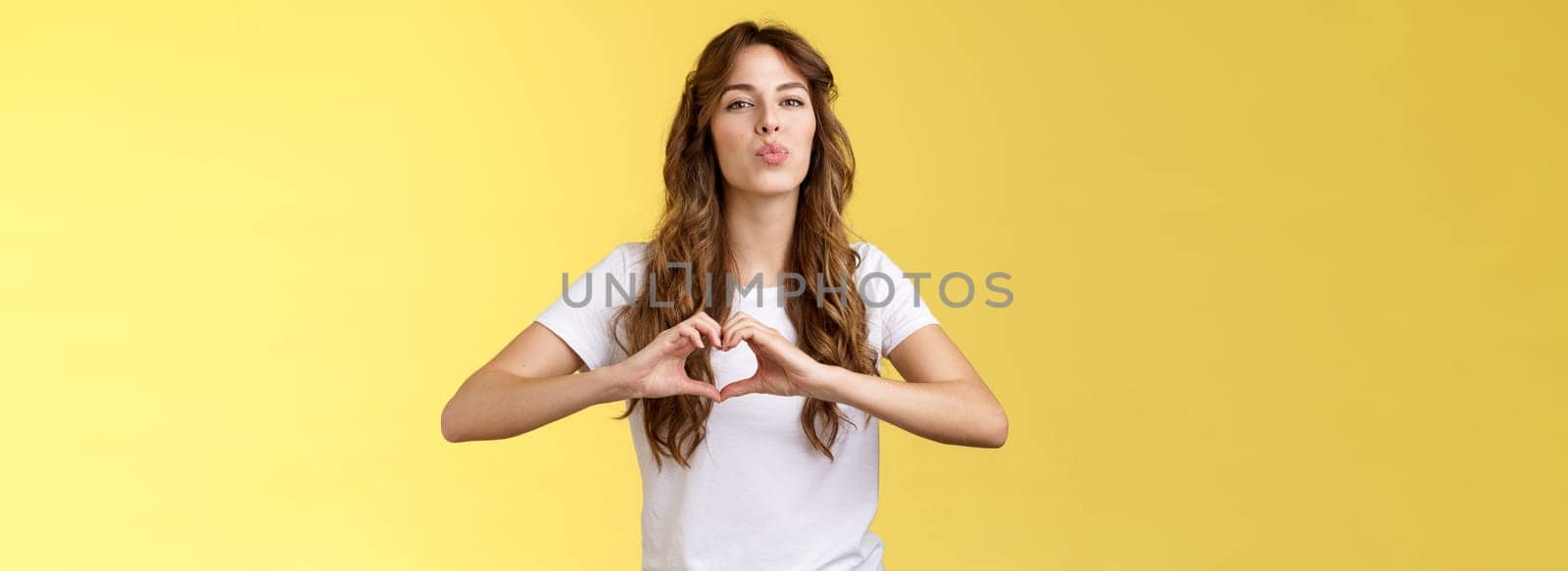 Passionate sensual attractive girlfriend express love sympathy show heart sign near chest folding lips kiss sending muah camera look admiration confess deep romantic feelings adore you by Benzoix