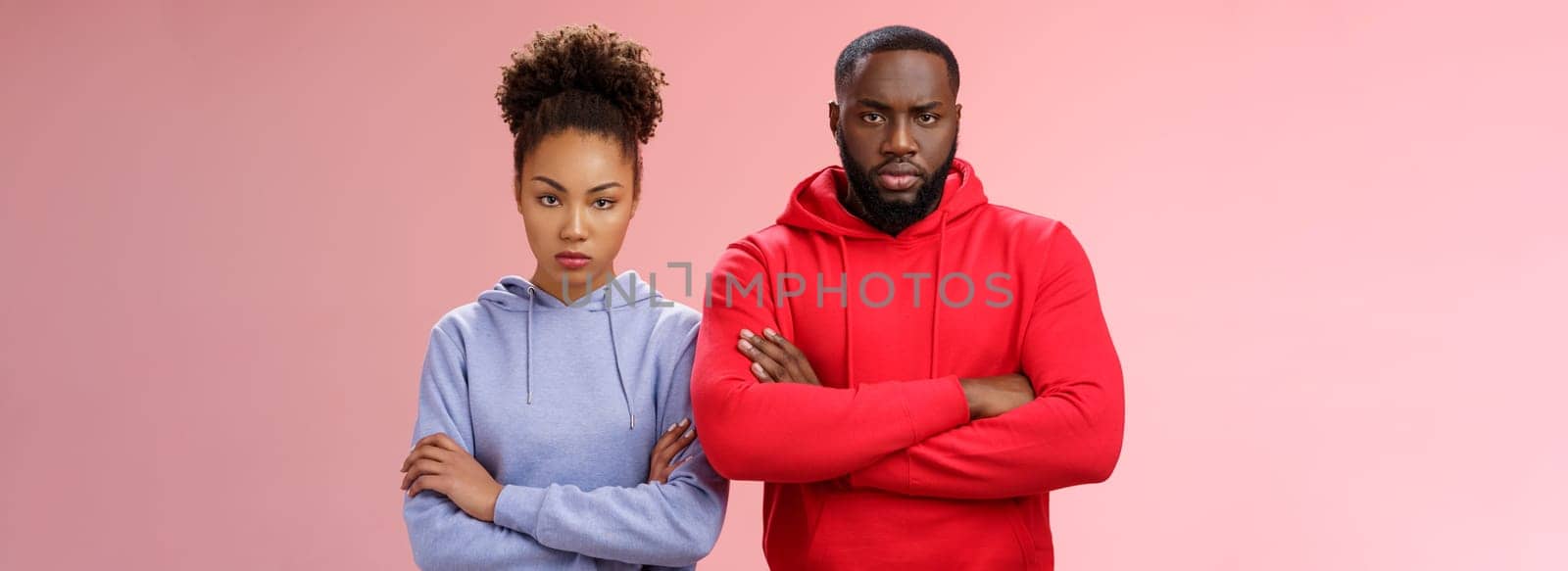 Two attractive african friends coworkers serious-looking standing confident strong pose arms crossed chest look determined focused camera wanna beat rival team computer game, self-assured.