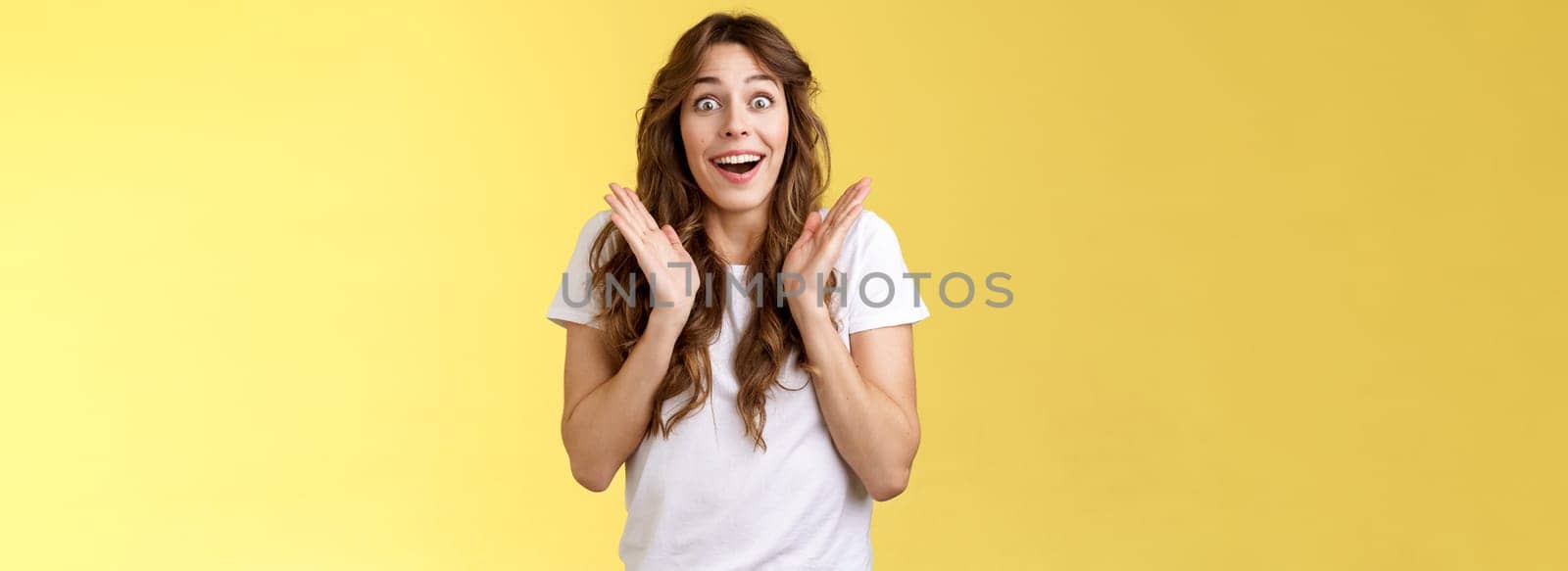 Surprised happy pleased impressed curly-haired girl gaze camera admiration satisfaction joy clap hands cheerful smiling broadly look camera fascinated enthusiastic applause yellow background by Benzoix