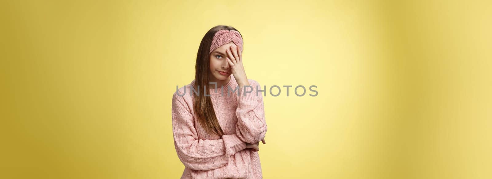 Woman facepalming covering face annoyed, bothered and inrritated, smirking looking with dismay, pissed off, posing unhappy displeased, staring indignant and upset posing tired over yellow background by Benzoix