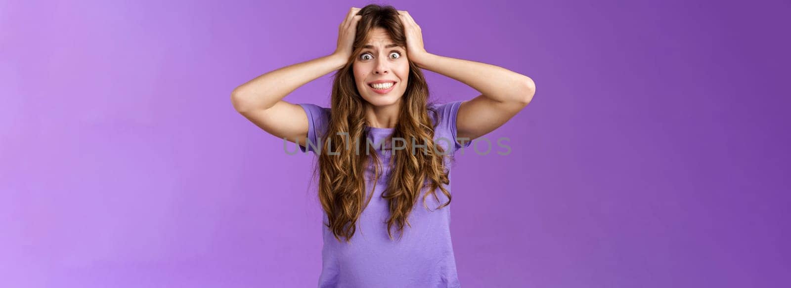 Girl feel panic troublesome perplexed situation clench teeth intense stare camera grab head distressed upset going insane crazy pissed popping eyes feel rage disappointment stand purple background. Lifestyle.