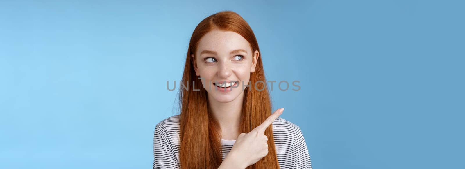 Intrigued good-looking redhead joyful curious girl watching looking upper left corner interested smiling broadly visit cool amusing place explore travelling new country astonished, blue background.