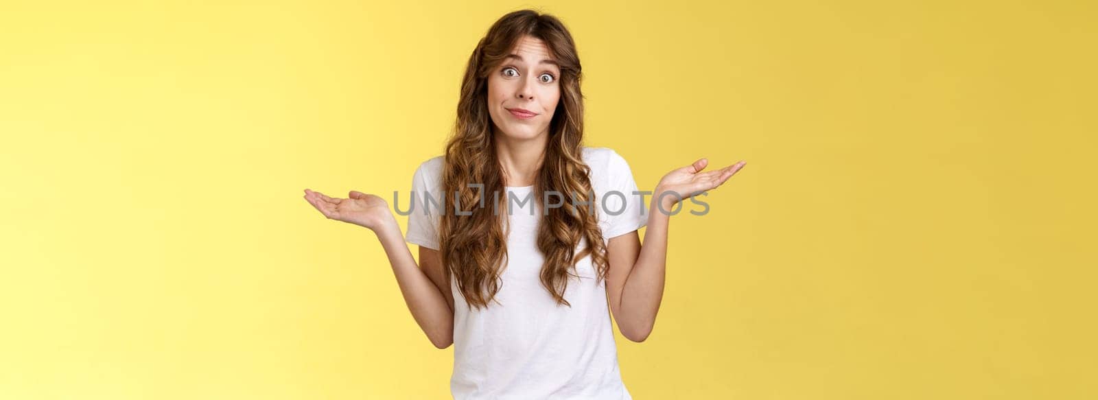 Sorry unable help. Clueless apathetic attractive female friend shrugging hands spread sideways full dibelief uncertain smirking unaware have no idea perplexed answer question yellow background.