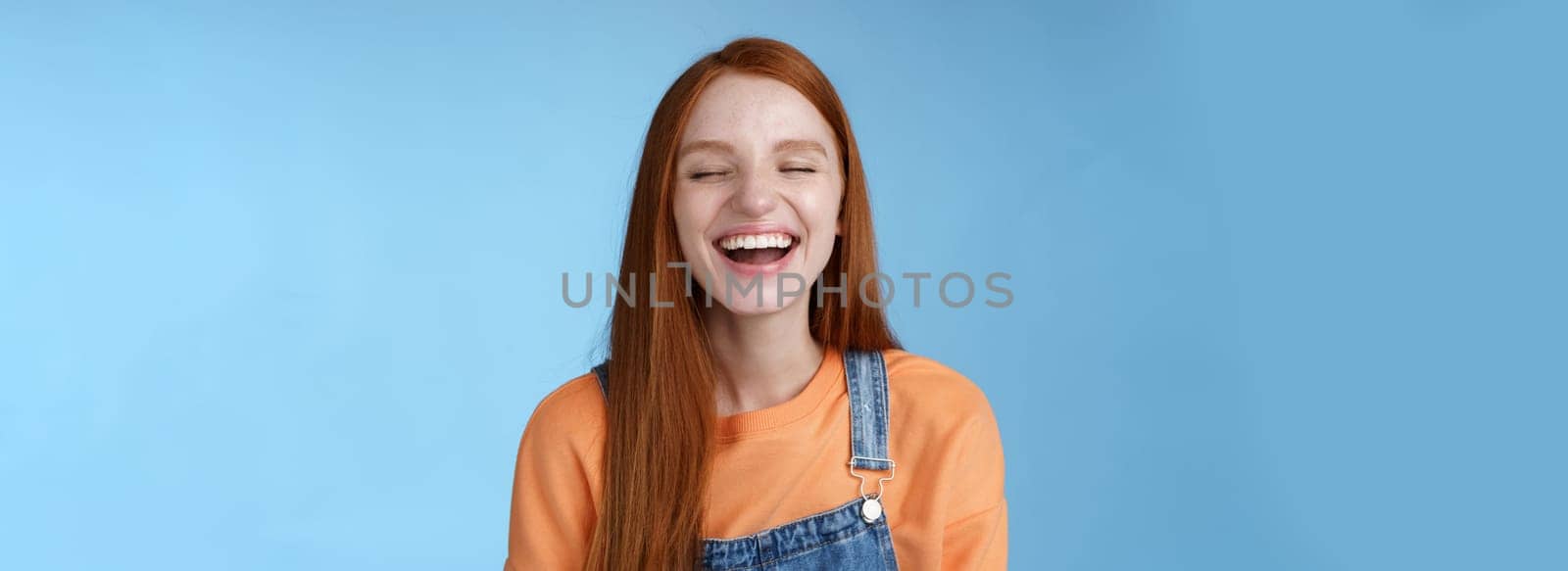 Carefree happy positive lucky redhead girl having fun close eyes smiling optimistic laughing out loud chuckling funny joke listen hilarious stories relaxing hang out friends, blue background.