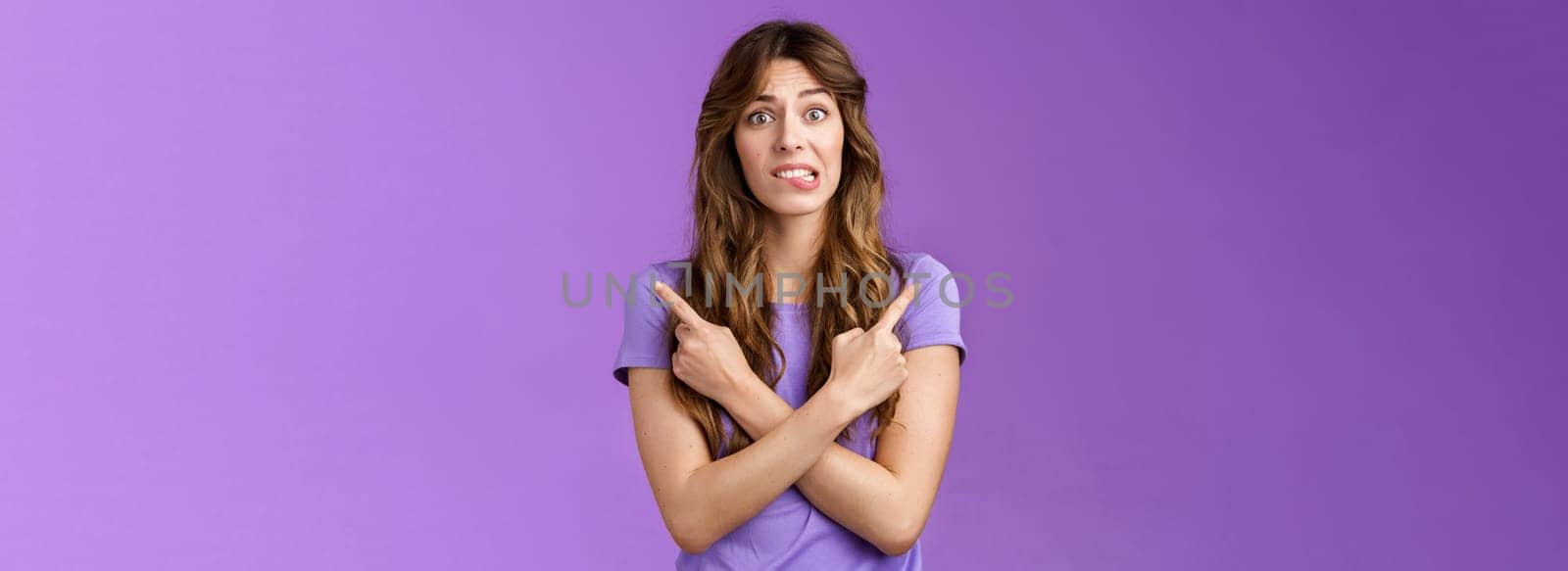 Perplexed timid hesitant worried girlfriend afraid making bad choice cross hands pointing sideways indicating left right perplexed decide frowning pull hesitant face asking advice purple background by Benzoix