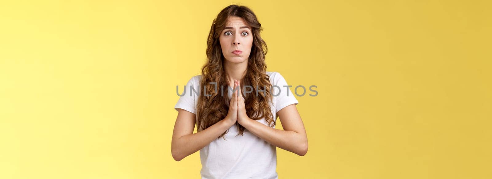 Pretty please beg you help me. Innocent cute lovely upset caucasian girl begging pleading your mercy pulling face hope for pity apologizing puppy eyes frowning need urgent advice yellow background.
