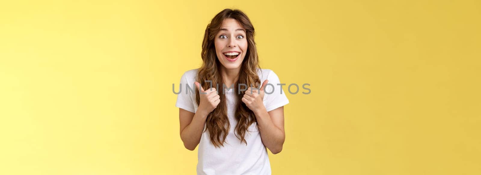 Lively excited happy cute european girl supportive give positive reply think event awesome smiling broadly show thumbs-up approval, accept great choice stand yellow background thrilled.