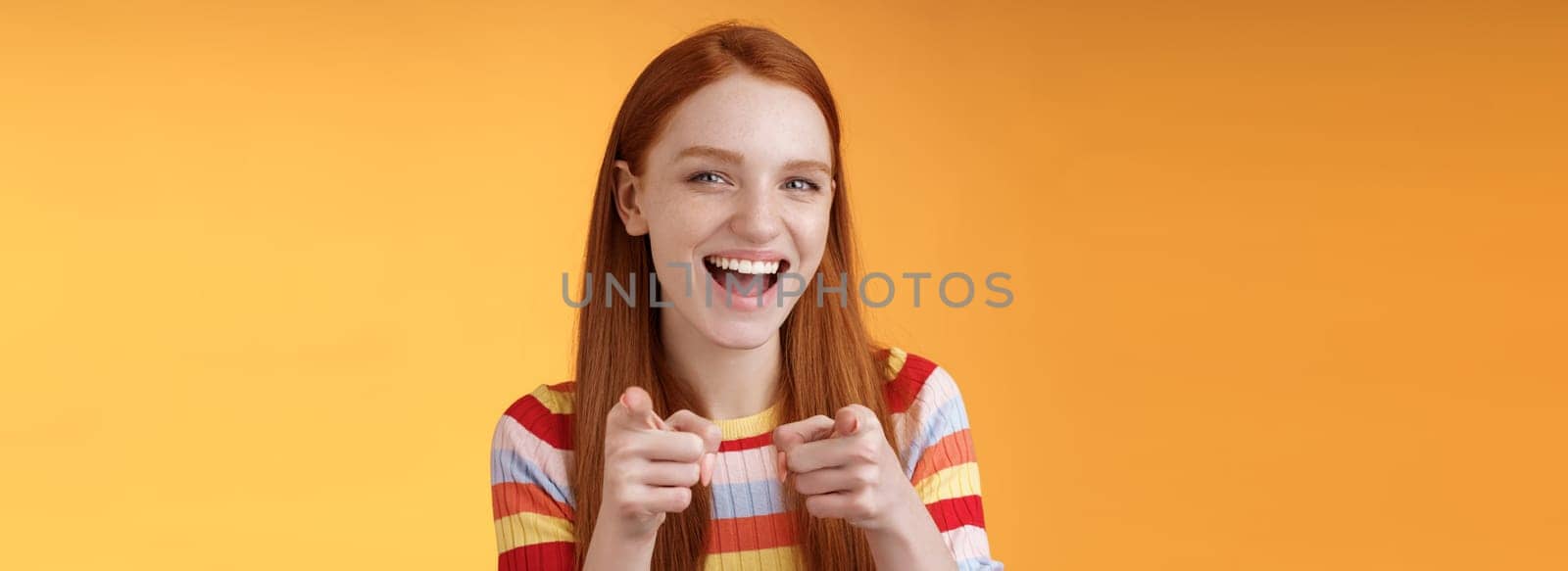 Enthusiastic carefree friendly redhead girl pointing finger-pistols camera smiling joyfully congratulating friend awesome choice cheeky greeting hinting girlfriend caught good opportunity by Benzoix