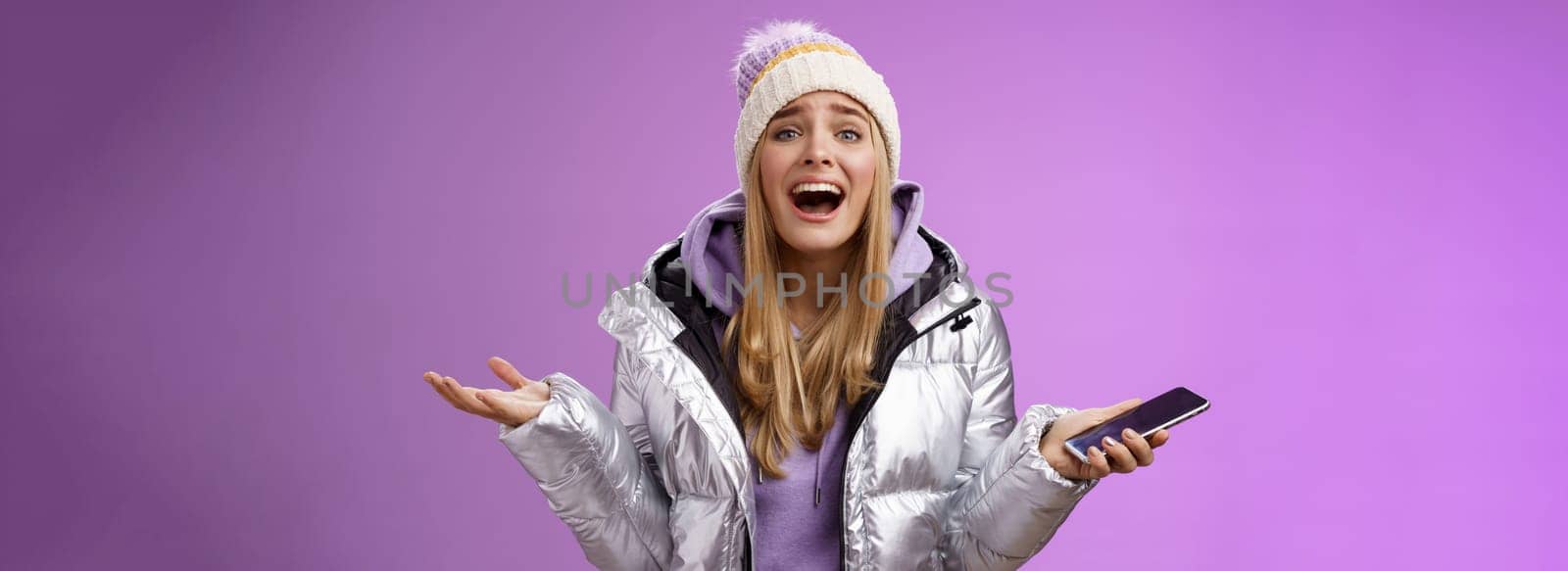 Girl upset yelling explaining missing chance lifetime feel regret speaking passionately spread hands sideways holding smartphone look bothered disappointed, standing purple background.