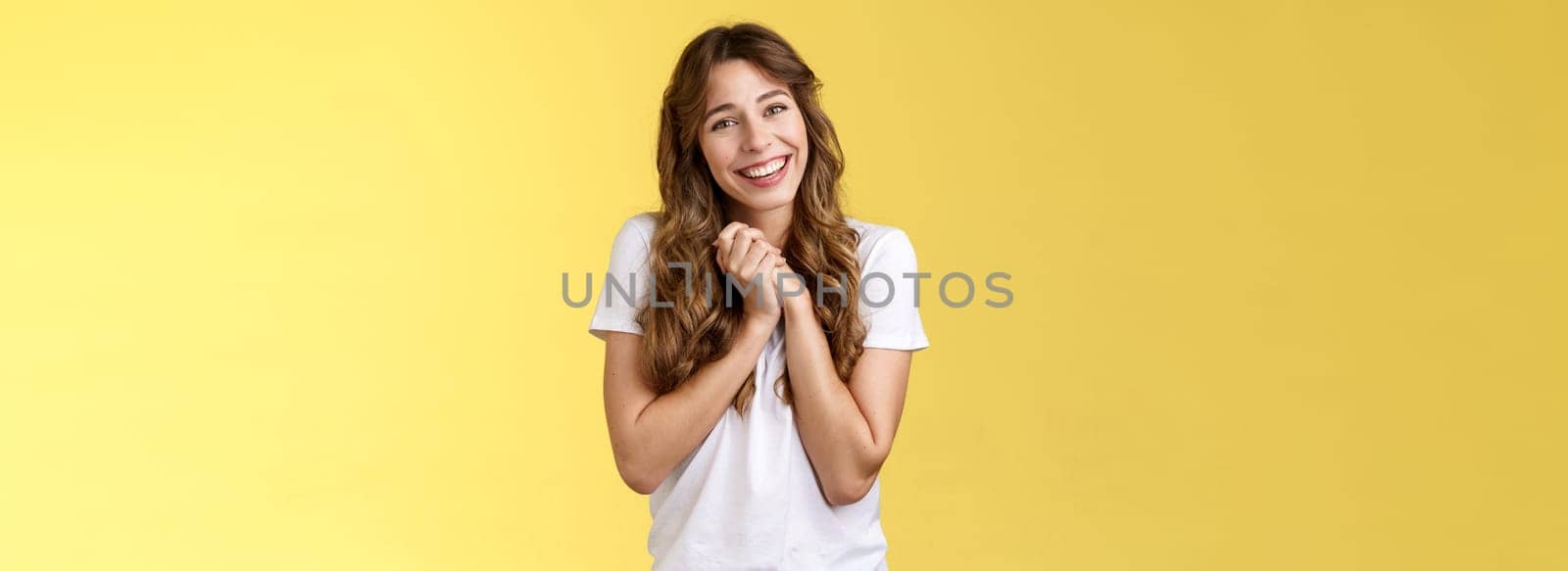 Tender lovely cute curly-haired girlfriend sighing happily clasp hands togehter appreciate touching perfect gift tilt head smiling broadly grateful thanking effort stand pleased yellow background. Lifestyle.