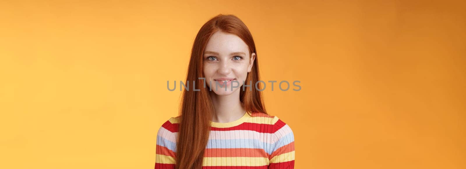 Pleasant friendly-looking confident smart redhead female student aim success smiling self-assured express lucky positive upbeat mood casually hang out orange background listening amusing story by Benzoix