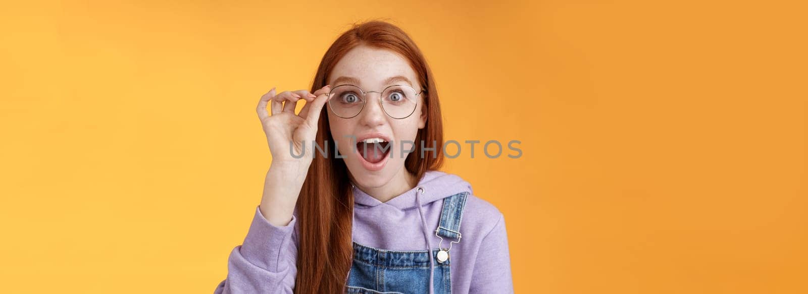 Omg so cool. Portrait amazed speechless excited redhead girl drop jaw amused stare camera surprised find out awesome product net touch glasses reading impressive post, orange background by Benzoix