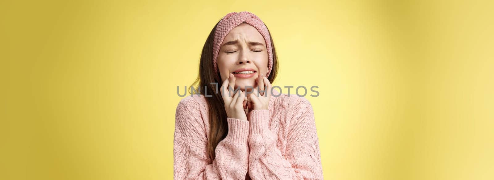 Worried, nervous tensed young cute girl in pink glamour headband, sweater, crossing fingers for good luck, clenching teeth, close eyes, anticipating miracle, having desire, wanting dream come true.