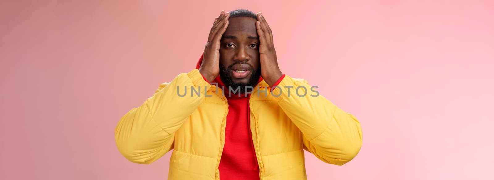 Shocked upset african-american bearded guy feel regret stunned hear terrible news hold hands head widen eyes stupor standing speechless troubled, look perplexed terribly sad, pink background.