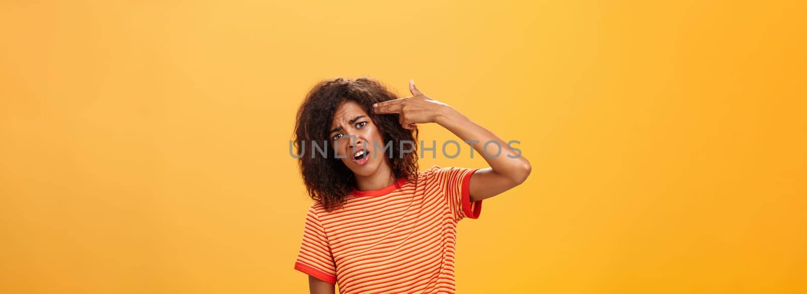 I would rather kill myself. Displeased bored and dissatisfied attractive bothered girlfriend in striped t-shirt tilting head, grimacing from dislike putting finger gun to forehead, commiting suicide by Benzoix