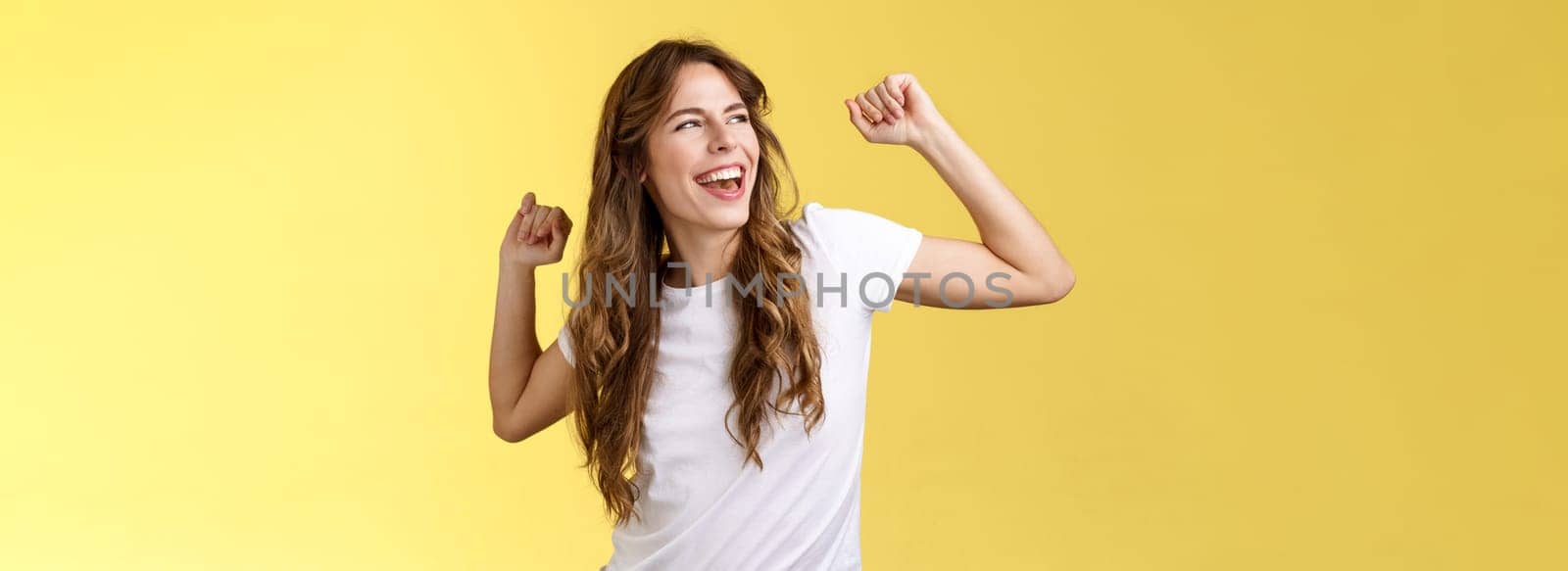 Yeah let perfect summer days behind. Daring good-looking happy charismatic young woman curly haircut gaze left pleased carefree having fun raise hands up celebratory victory winning success.