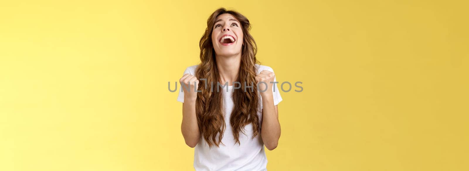 God finally yes. Relieved thankful pleased happy girl look up thank god fist pump celebration success win triumphing clench arms grateful delighted lucky opportunity stand yellow background by Benzoix