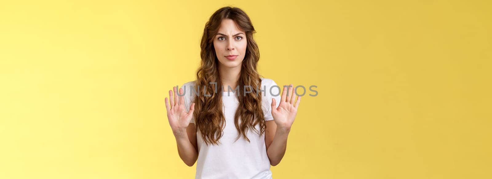 No thats enough. Serious-looking confident woman restrain man demand stay away give refusal look intense prohibit rejecting suspicious unpleasant offer stand yellow background by Benzoix