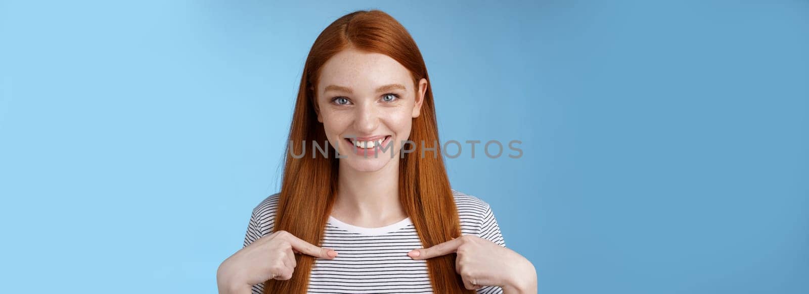 Me seriously. Glad surprised happy carefree redhead tender feminine girl pointing herself smiling laughing amused picked chosen participate performance standing thrilled joyful blue background.