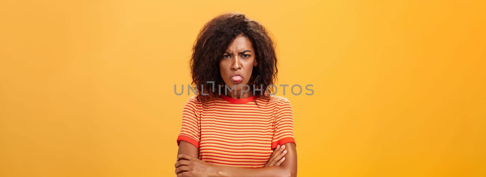 You offended me apologize. Displeased childish attractive adult woman in striped t-shirt holding hands crossed sticking out tongue and frowning having bad temper being dissatisfied and angry by Benzoix
