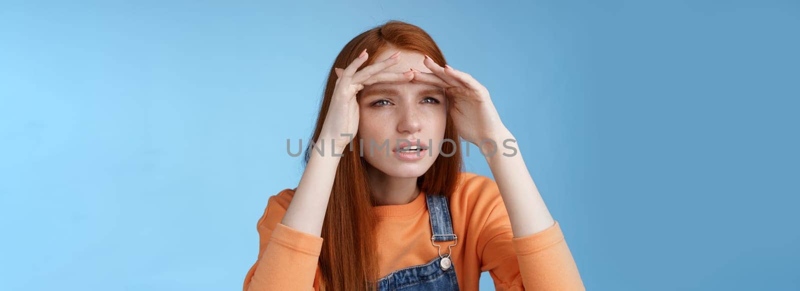 Worried clingy redhead girlfriend spying boyfriend peer from distance squinting focus sight look afar hold hands forehead cover eyes sunlight standing concentrated blue background by Benzoix