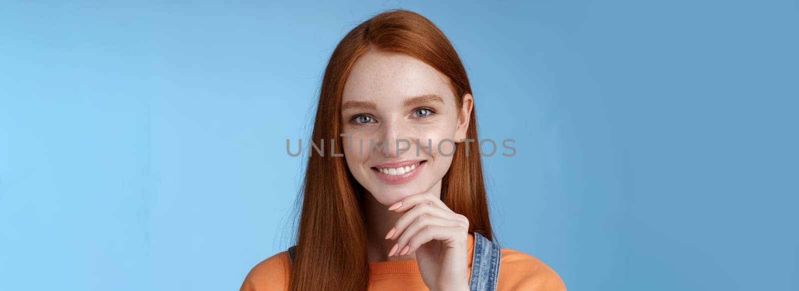 Curious smart creative young female redhead blue eyes have perfect idea how spend summer vacation smiling joyful look intrigued thoughtful touch chin pondering choice, standing blue background by Benzoix