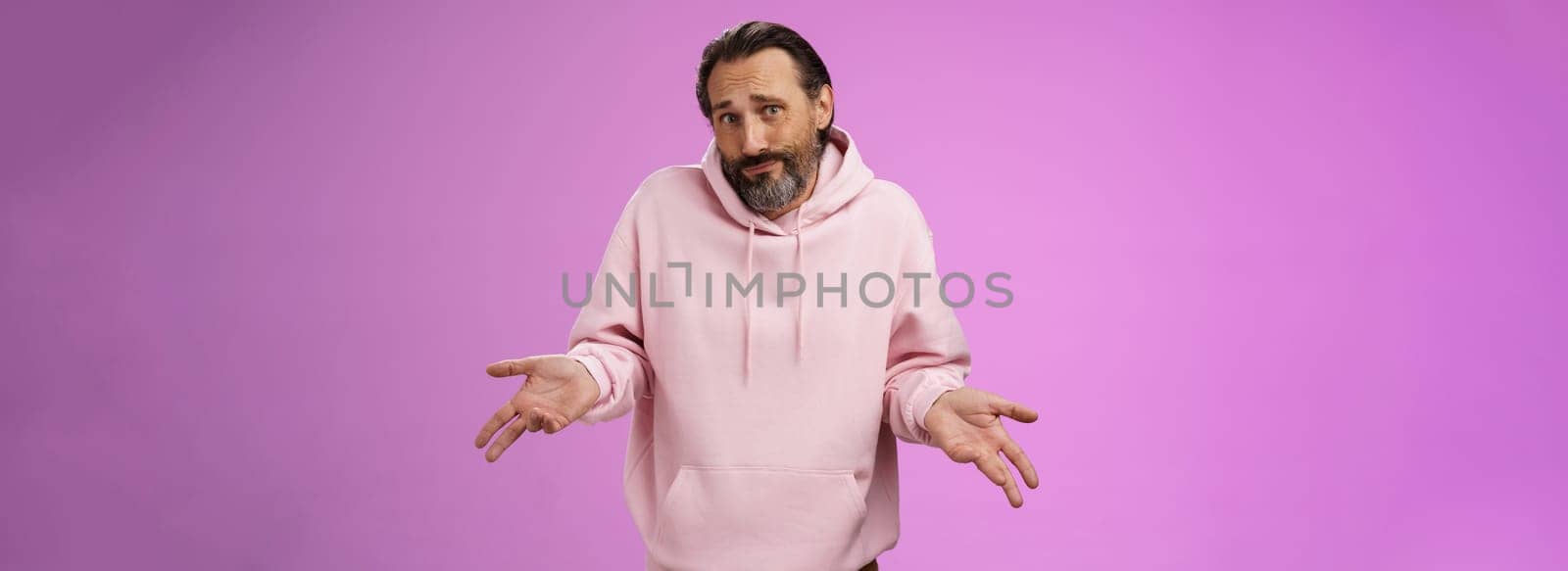 Portrait clueless unaware father cringing smirking uncertain shrugging hands spread sideways no idea, look questioned doubtful cannot answer unknown topic, standing purple background.
