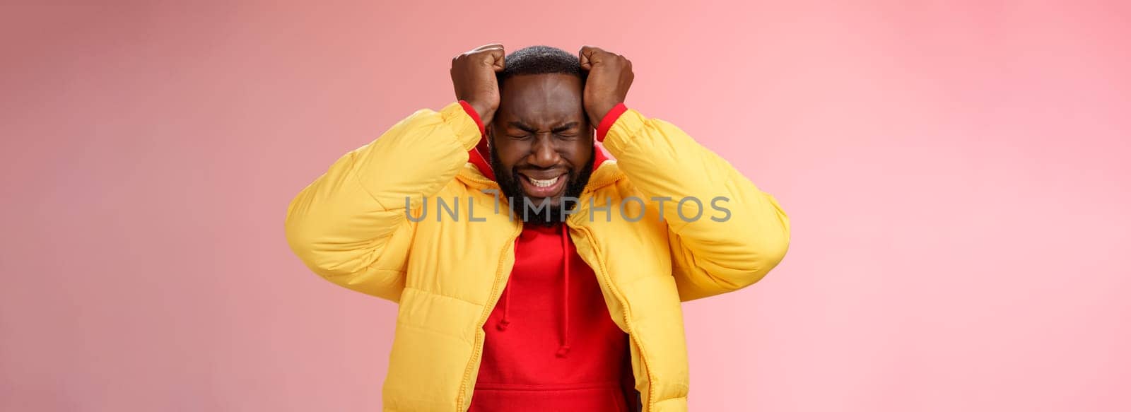 Depressed heartbroken black bearded boyfriend go crazy pissed squeez head frowning squinting clenching teeth painful feeling inside standing devastated distressed pink background suffering headache by Benzoix