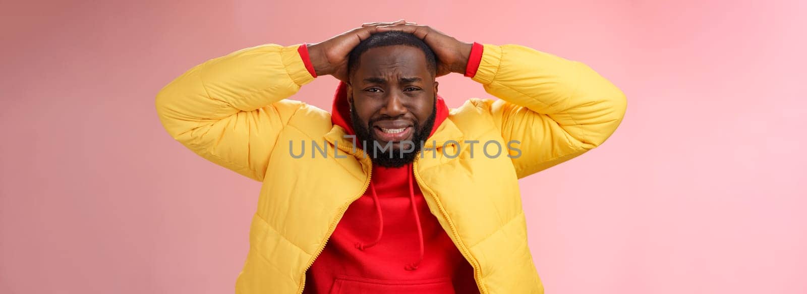Upset unhappy african-american male entrepreneur lose money feel regret sadness grimacing painful heartbreaking feelings, holding hands head depressed devastated, standing pink background.