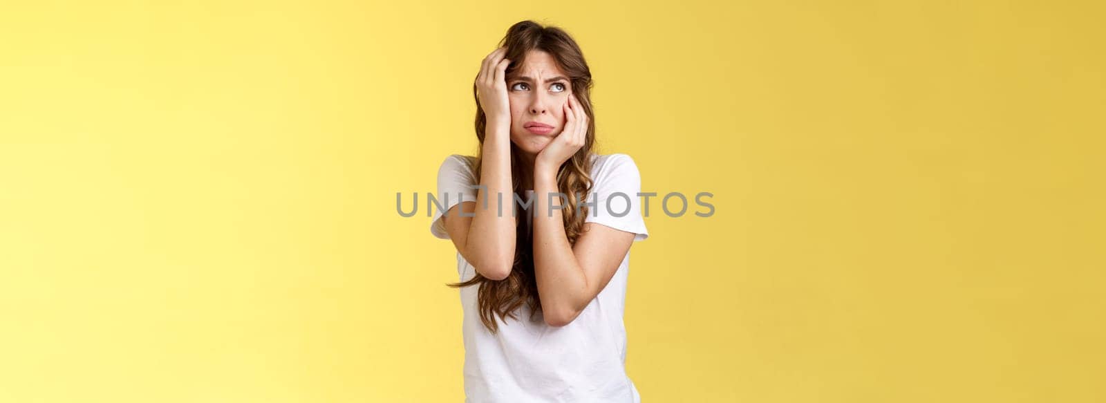 Shocked timid insecure young panicking woman wanna cry standing anxious frightened grab head both hands freak out look away praying for help terrified stand yellow background horrified by Benzoix