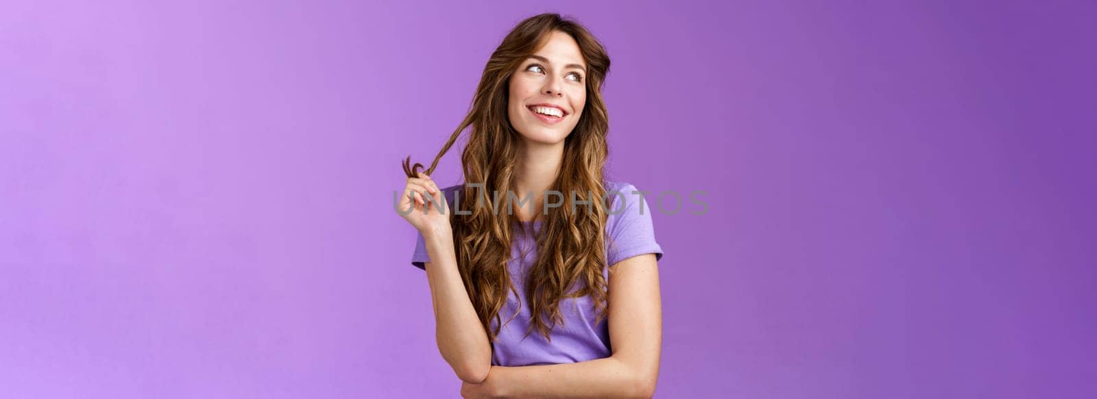 Lively arrogant good-looking girl curly stylish haircut look away dreamy delighted daydreaming thoughtful gaze away touch hair strand rolling curly smiling broadly stand purple background by Benzoix