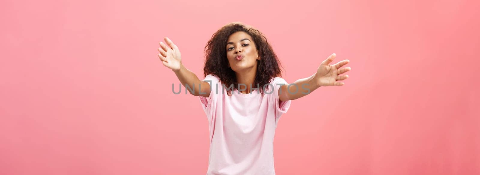 Come closer let me hug you. Portrait of passionate confident and happy good-looking african american woman with curly hairstyle folding lips pulling hands towards camera to cuddle and give kiss. Relationship and feelings econcept