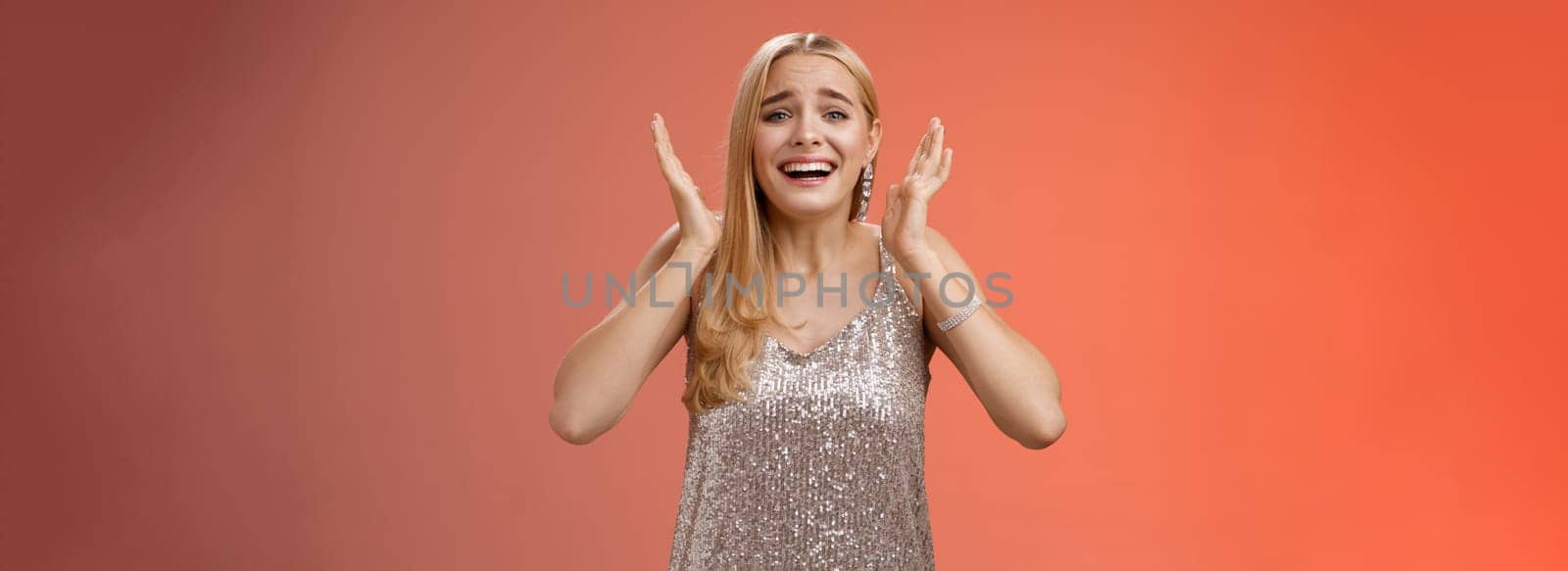 Lifestyle. Amazed freaked out excited blond female fan see favorite celebrity star screaming astonished happy look emotive wanna cry happiness waving palms near head thrilled red background.